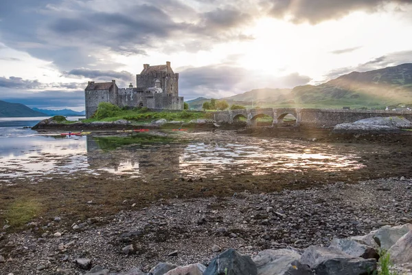 Eilean Donan Castle durante o pôr do sol, enquanto as canoas passam Dornie, Escócia — Fotografia de Stock