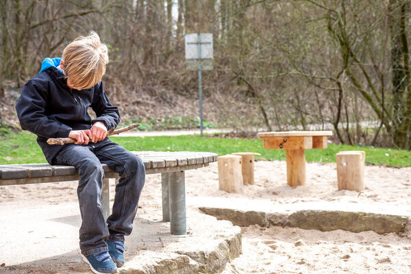 A boy carving and playing with with woodblock