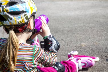 Silindir-bıçaklar oturan ve maden suyu içme ve yemek yeme giyen küçük kız