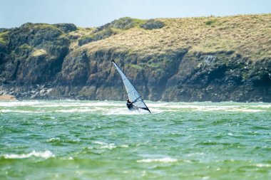 Rüzgar sörfçü Newborough Warren arka plan, Anglesey Adası, Kuzey Galler, İngiltere'de Llanddwyn Adası ile plajda sahiptir