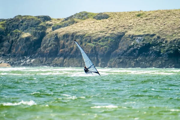 Windsurfer genießt den Strand von newborough warren mit der Insel llanddwyn im Hintergrund, isle of anglesey, north wales, uk — Stockfoto