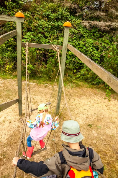 Liten pojke och flicka klättrar på nätet leddar i äventyrspark — Stockfoto