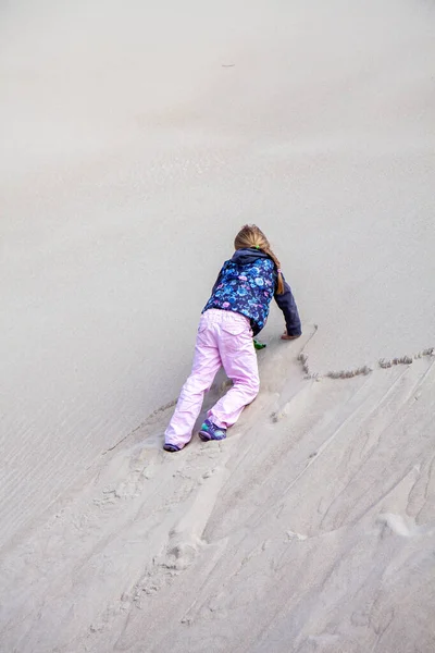 Маленькая девочка взбирается на дюну летом — стоковое фото