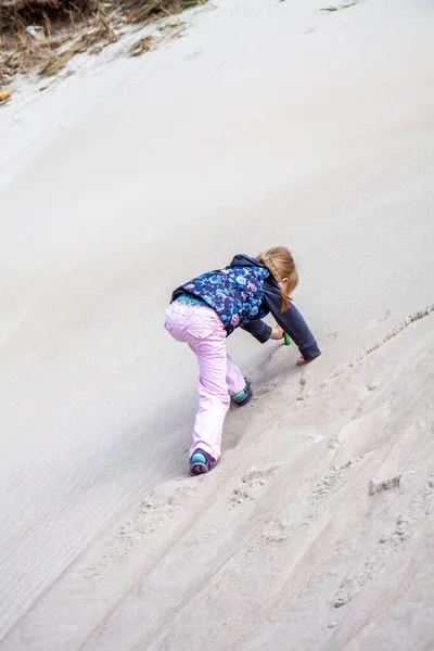 Liten flicka klättrar upp sanddyn på sommaren — Stockfoto
