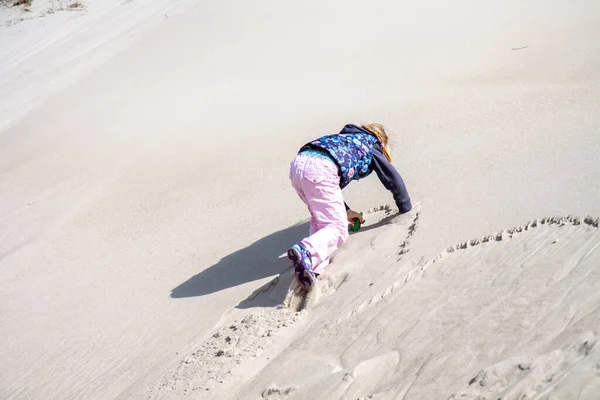 Маленькая девочка взбирается на дюну летом — стоковое фото