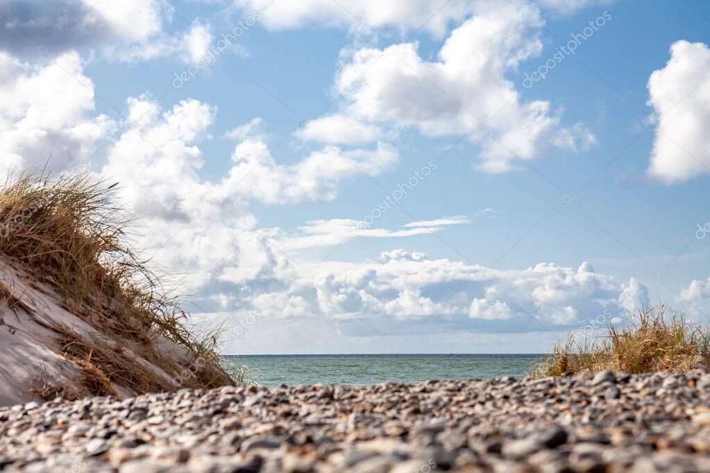 Beautiful sand dune with sea grass and sailboat on horizon.