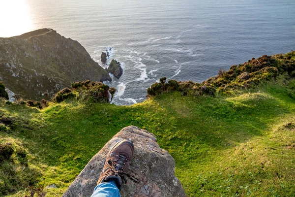 Feet trekking boots on rocky cliff edge — Stock Photo, Image