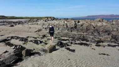 Güzel bayan kumlu kumsalda yürüyor