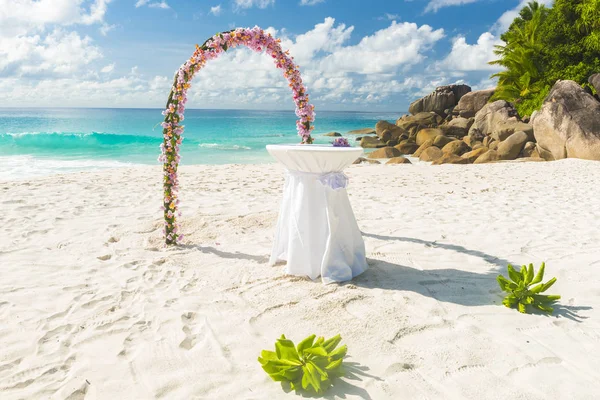 Floral garland and a white table as wedding decorations on a tropical beach Anse Georgette on Praslin island in the Seychelles