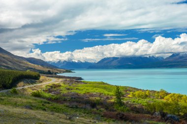 Mighty Mt. Aşçı, Yeni Zelanda 'daki inanılmaz mavi Pukaki gölünün yakınındaki bulutlardan çıkıyor.