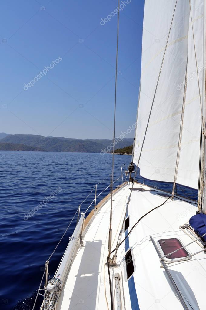 Ultramarine blue water and land viewed from deck of yacht.