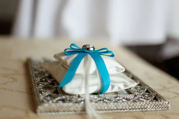 Wedding rings on a cushion with blue ribbon — Stock Photo, Image