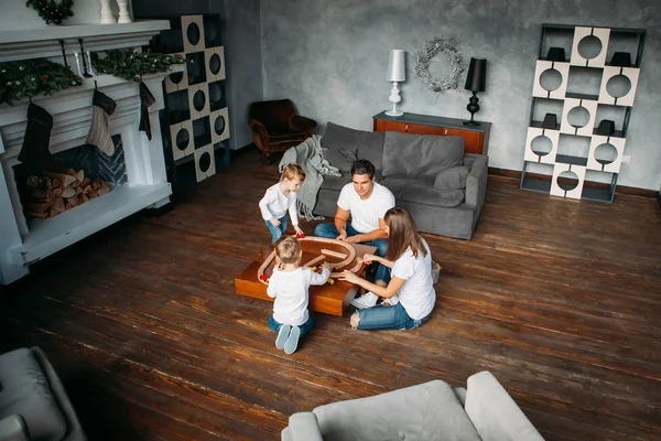 Feliz familia jugando con juguete ferrocarril carretera en casa —  Fotos de Stock