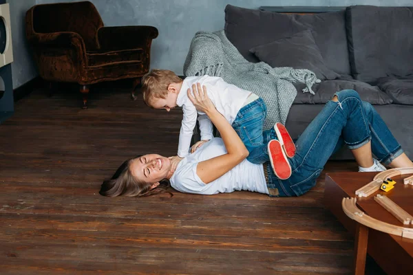 Linda madre y su hijo jugar en el suelo juntos interior —  Fotos de Stock