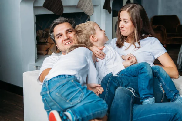 Padre y madre tumbados en el sofá y jugando con dos hijos pequeños —  Fotos de Stock