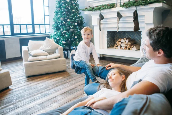 Father and mother lying on the sofa and playing with little son — Stock Photo, Image