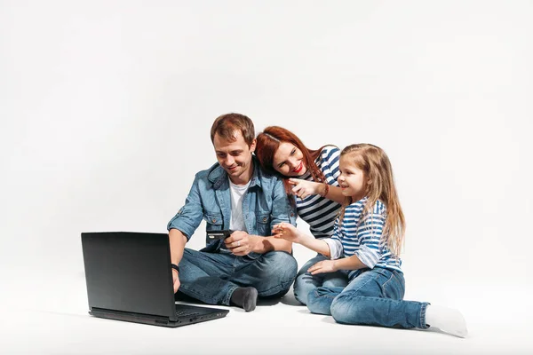 Famille heureuse Père, mère et enfant couchés sur le sol avec ordinateur portable et carte de crédit sur fond blanc isolé — Photo
