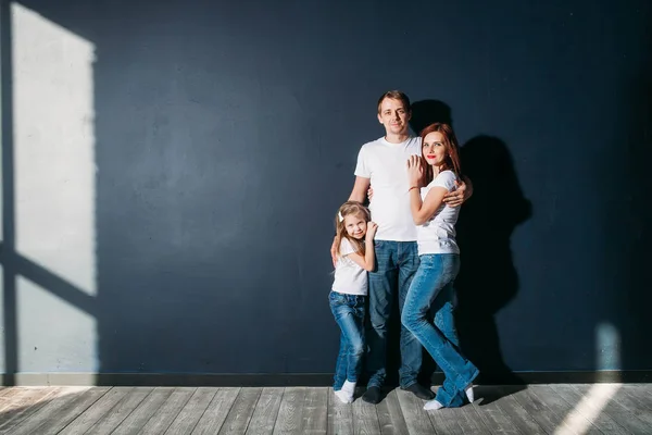 Feliz retrato familiar de pie sobre fondo gris piso de madera habitación ventana día soleado — Foto de Stock