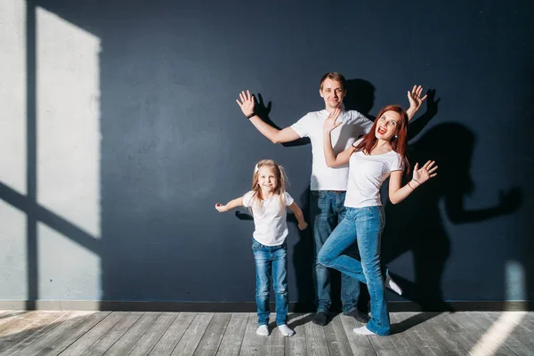 Lycklig familj porträtt stående på grå bakgrund trä-golv rum fönster solig dag — Stockfoto