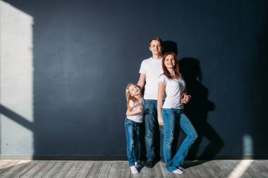 Mutlu aile portresi ayakta gri arka plan ahşap zemin oda pencere güneşli