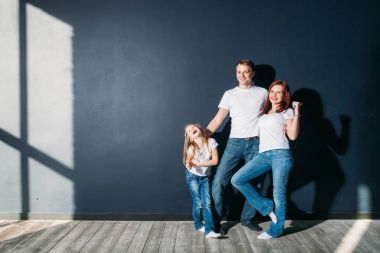 Mutlu aile portresi ayakta gri arka plan ahşap zemin oda pencere güneşli