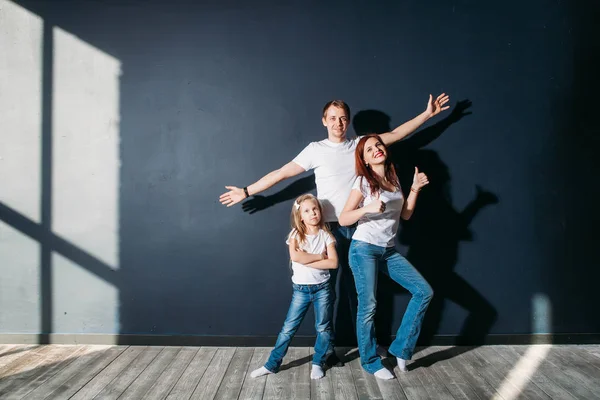 Feliz retrato familiar de pie sobre fondo gris piso de madera habitación ventana día soleado — Foto de Stock