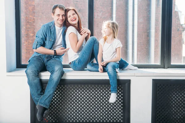 Happy family mother father child portrait sitting on window sill — Stock Photo, Image