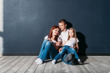 Mutlu aile portresi gri arka plan ahşap zemin oda pencere güneşli günde siting