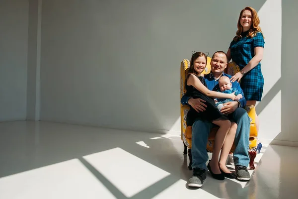 Aile portre fotoğraf bir anne baba küçük oğlu ve kızı ile oturup koltuk beyaz arka plan üzerinde gülümseyen içinde — Stok fotoğraf