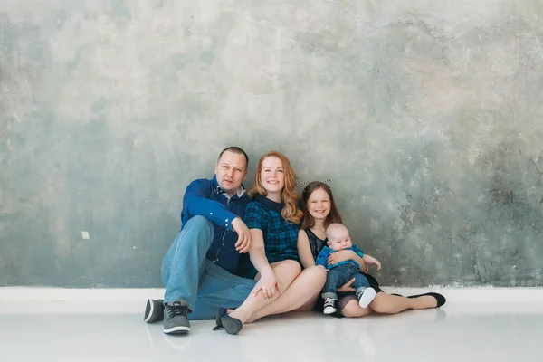 Feliz familia retrato sentado en gris fondo blanco piso habitación día soleado — Foto de Stock