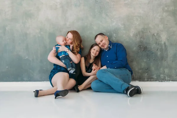 Feliz familia retrato sentado en gris fondo blanco piso habitación día soleado —  Fotos de Stock