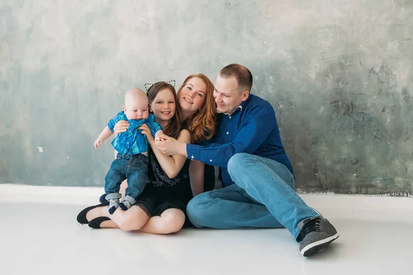 Feliz familia retrato sentado en gris fondo blanco piso habitación día soleado —  Fotos de Stock