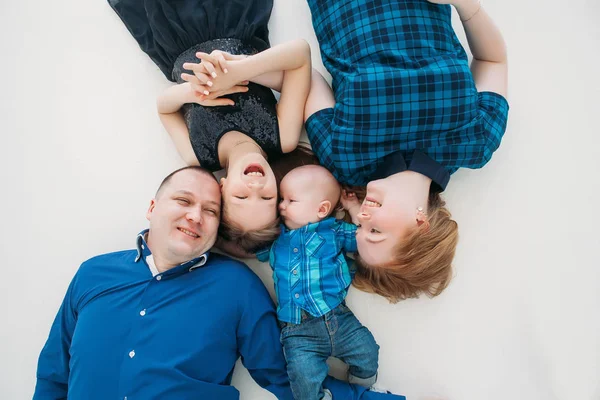 Feliz familia madre padre hija hijo retrato acostado en blanco piso habitación estudio azul — Foto de Stock