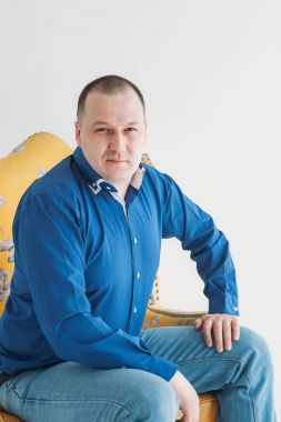 Sandalyenin üstünde siyah elbise siting gülümseyen yakışıklı adam