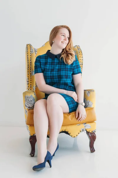 Krásná mladá žena dívka s úsměvem v černých šatech sedící na židli — Stock fotografie