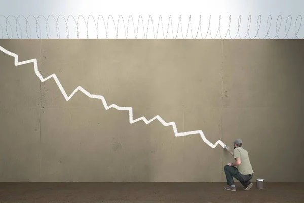 Een man tekent een dalende grafiek op een grens barrière. — Stockfoto