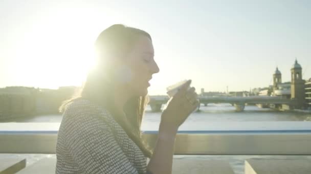 在伦敦伦敦桥上 一位迷人的高加索裔女商人在日落时分喝咖啡 她的镜头定格在镜头前 — 图库视频影像