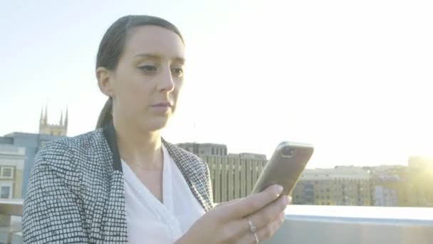 在伦敦伦敦桥上 一位迷人的高加索女商人在日落时用智能手机走路 — 图库视频影像