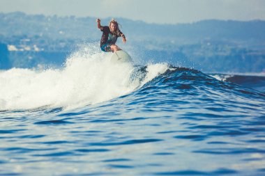 Erkek sörfçü bir dalga ile lots-in su spreyleri Bali, Endonezya yakalamak