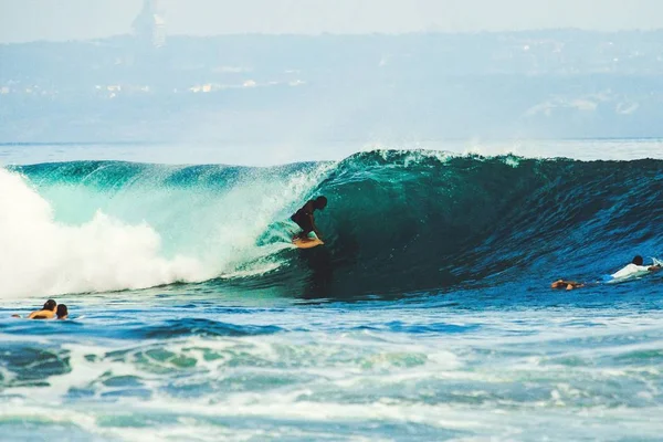 Surfers catching breaking wave in Bali