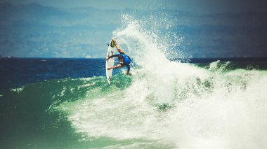Erkek sörfçü bir dalga ile lots-in su spreyleri Bali, Endonezya yakalamak