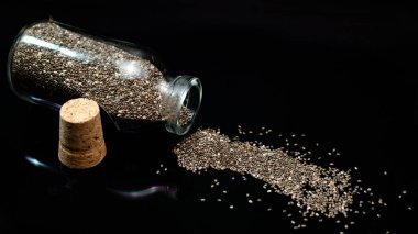 Siyah arka planda sağlıklı chia tohumları ve cam kavanoz 