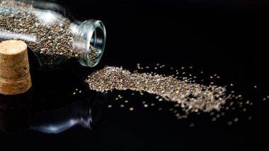 Siyah arka planda sağlıklı chia tohumları ve cam kavanoz