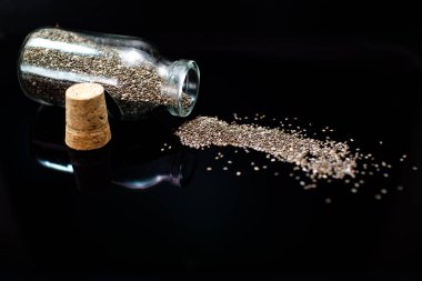 Siyah arka planda sağlıklı chia tohumları ve cam kavanoz