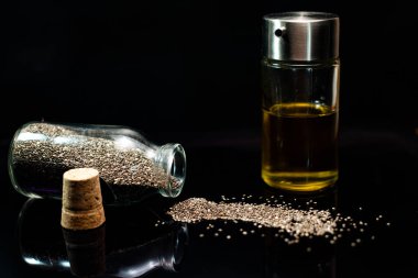 Siyah arka planda cam kavanozlardaki chia tohumları ve yağın yakın plan görüntüsü