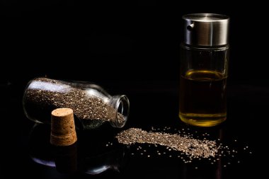 Siyah arka planda cam kavanozlardaki sağlıklı chia tohumları ve yağın yakın plan görüntüsü