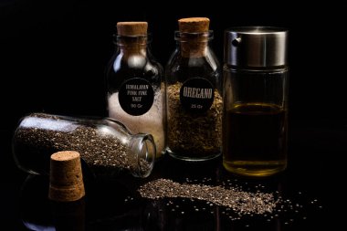 Farklı tohumların, baharatların ve yağın siyah arka plandaki kavanozlarda yakın plan görüntüsü