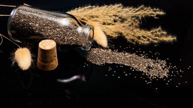 Siyah zemin üzerinde chia tohumları ve cam kavanoz