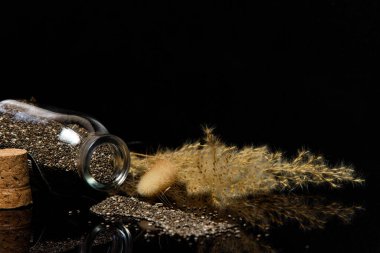 Siyah zemin üzerinde chia tohumlarının ve cam kavanozun yakın plan görüntüsü