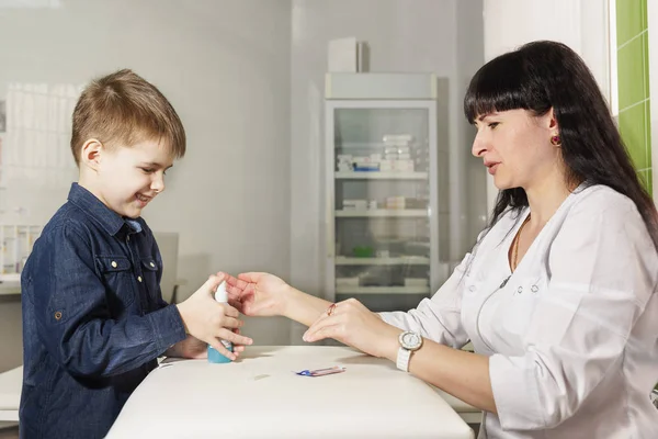 Mother - nurse teaches little son to disinfect wounds with spray for cuts. Child at work with mom